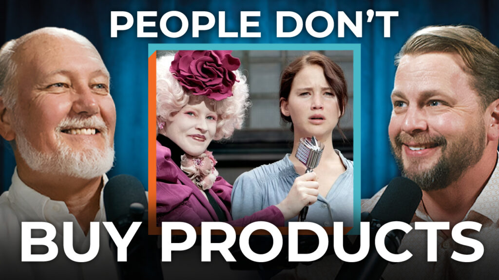 Three people hold microphones in front of a "Hunger Games" scene with the text: "People Don't Buy Products," discussing buying psychology and consumer identity's impact on sales.