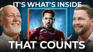Two men smile at microphones, with an Iron Man photo between them. Text reads, "It's what's inside that counts," emphasizing that overcoming objections is crucial to building businesses from the ground up.