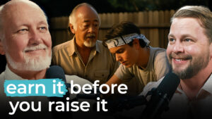 Four people—three men and one teen—hold microphones. The quote on screen reads, "Earn the right before raising prices.